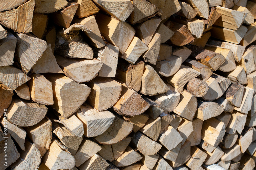 Tightly stacked firewood lies in a large pile. Prepared firewood for heating the house Tightly stacked firewood lies in a large pile. Prepared firewood for heating the house