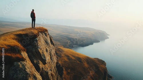 Close-up of a traveler standing on a cliff, overlooking a panoramic view of rolling hills and a distant ocean, evoking feelings of adventure and freedom