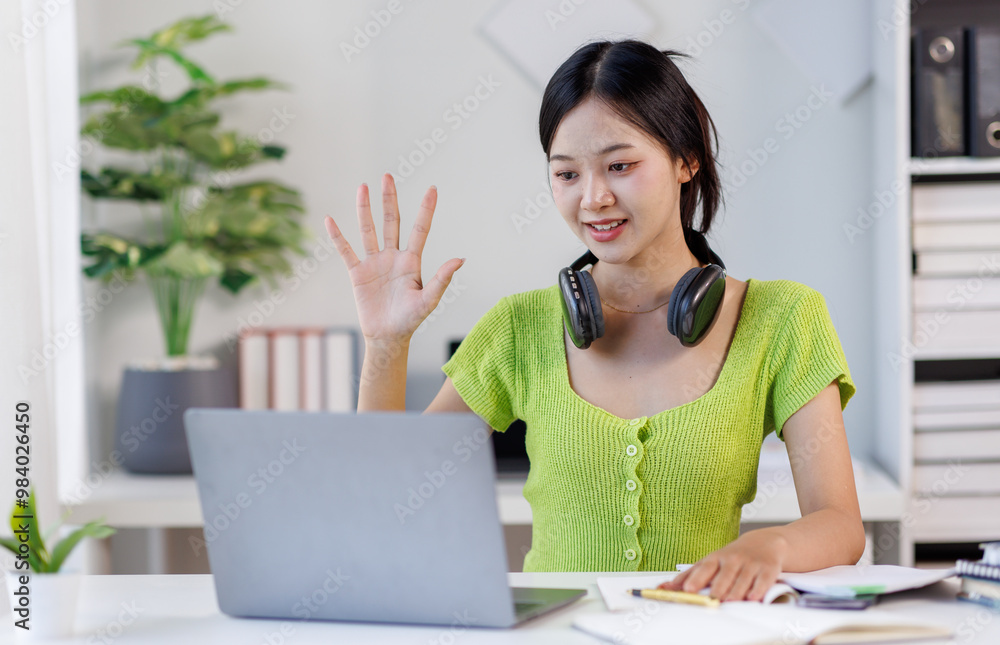 Asian female student or office worker studying online wearing headphones and use laptop taking notes in notebook sitting at the home ofice
Asian female student or office worker studying online wearing headphones and use laptop taking notes in notebook sitting at the home ofice