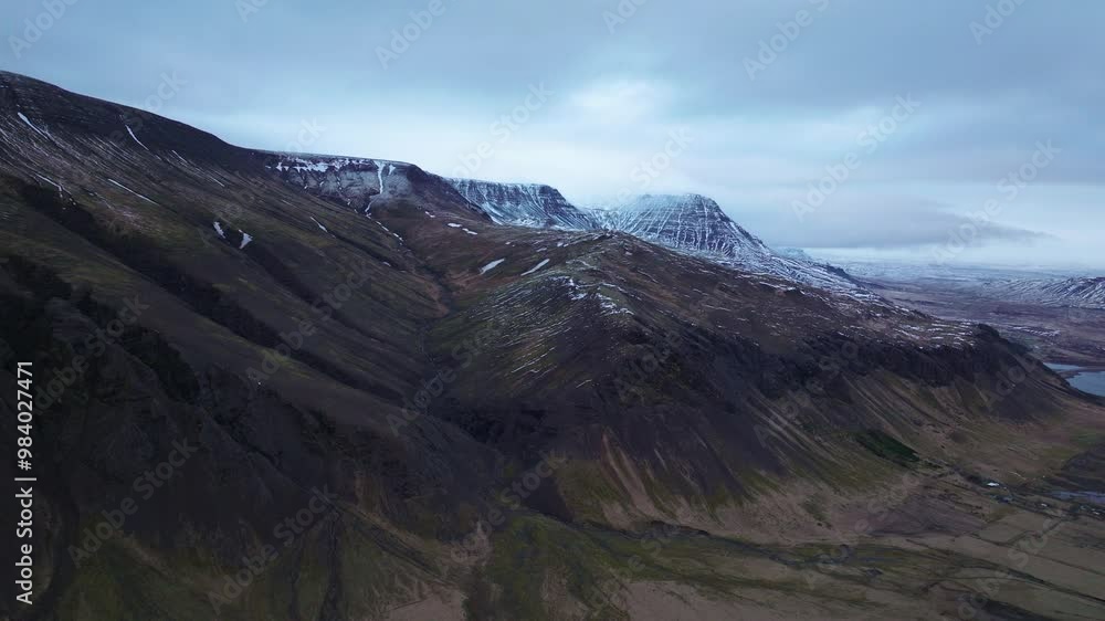 Aerial view of a snow-dusted mountain range in Akranes, Iceland, with rugged peaks and dramatic skies at dusk, capturing the serene Icelandic wilderness. Aerial view of a snow-dusted mountain range in Akranes, Iceland, with rugged peaks and dramatic skies at dusk, capturing the serene Icelandic wilderness.