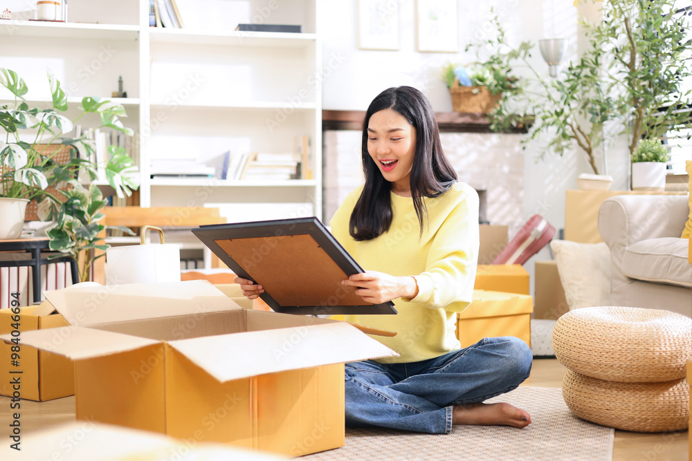 Cute asian woman is preparing a picture frame for home decoration in shopping box to send to customer who ordered online. Cute asian woman is preparing a picture frame for home decoration in shopping box to send to customer who ordered online.