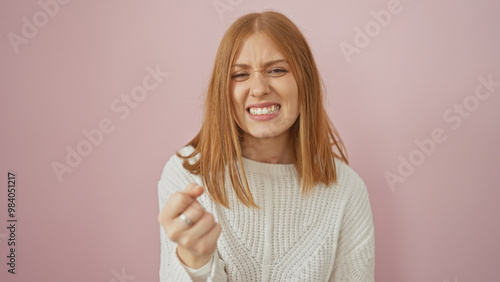 Young redhead woman showing disdain over isolated pink background.