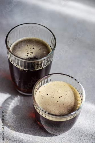 Two Glasses of Kvass Drink on a Light Surface with Shadows