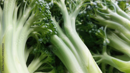 Top view of fresh, organic broccolini and green baby broccoli florets, a raw, vegan superfood on a light background