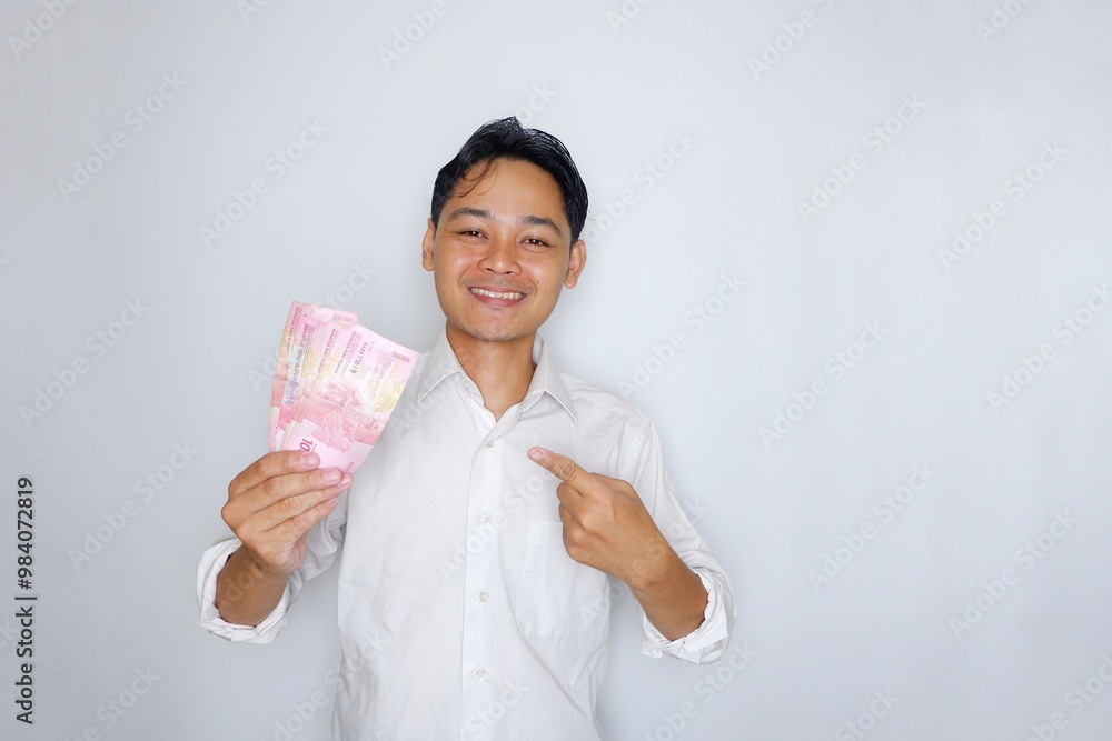 Random expression of adult Asian Indonesian man while holding banknotes isolated on white background Random expression of adult Asian Indonesian man while holding banknotes isolated on white background