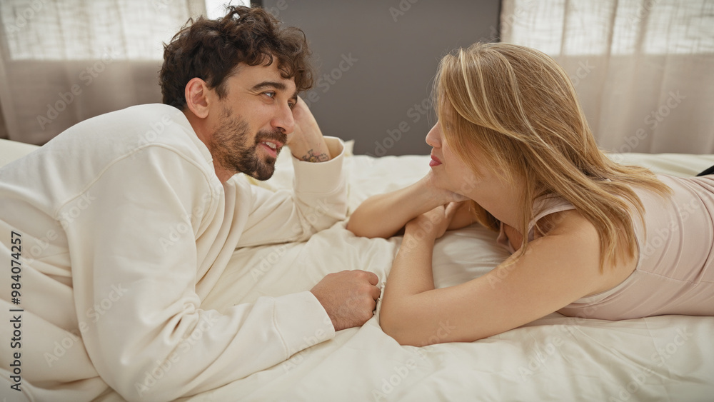 A loving couple enjoys a tender moment together, lying on a bed in a cozy, warmly-lit bedroom. A loving couple enjoys a tender moment together, lying on a bed in a cozy, warmly-lit bedroom.