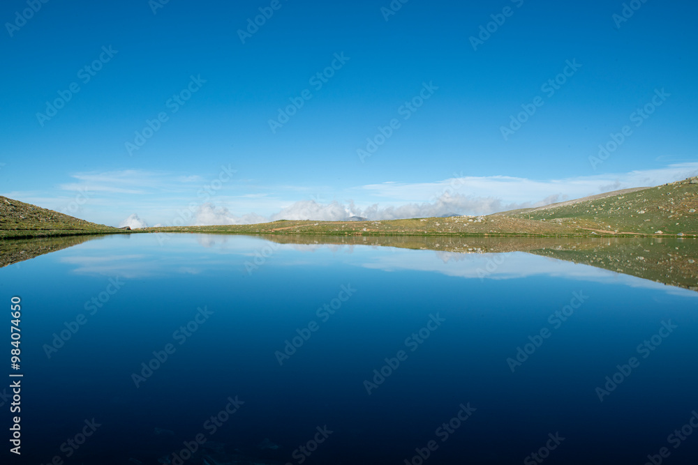 Reflection of clouds in the blue sky in the lake.Reflections in the glacial lake. Reflections on Kilimli lake. Lakes on top of Uludağ, Kilimli Lake, Bursa, Türkiye. Reflection of clouds in the blue sky in the lake.Reflections in the glacial lake. Reflections on Kilimli lake. Lakes on top of Uludağ, Kilimli Lake, Bursa, Türkiye.