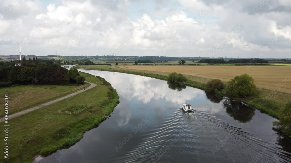 A River Boat Sailing around a river bend of the River Trent. Drone video follows the boat around the bend and shows the wonderful countryside surroundings of Nottinghamshire. A River Boat Sailing around a river bend of the River Trent. Drone video follows the boat around the bend and shows the wonderful countryside surroundings of Nottinghamshire.