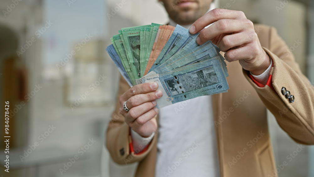 Φωτογραφία Handsome bearded man holding malaysian ringgit with city street background, portraying financial concept in an urban setting