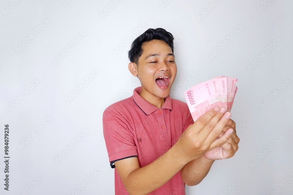 Random expression of adult Asian Indonesian man while holding banknotes isolated on white background Random expression of adult Asian Indonesian man while holding banknotes isolated on white background
