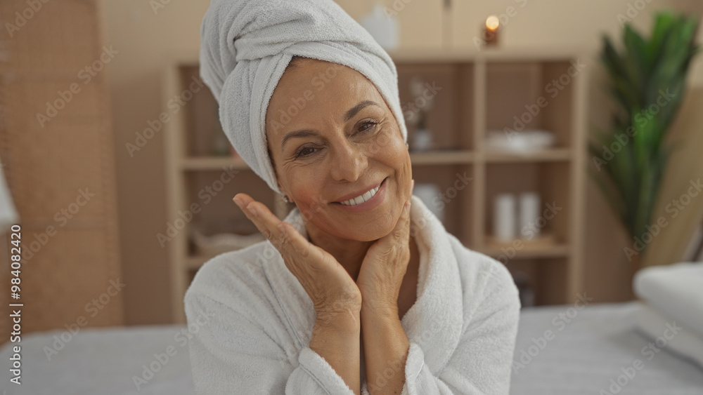 Woman smiling in a relaxing spa setting with a towel head wrap and robe, showcasing mature beauty and wellness in an indoor salon environment. Woman smiling in a relaxing spa setting with a towel head wrap and robe, showcasing mature beauty and wellness in an indoor salon environment.