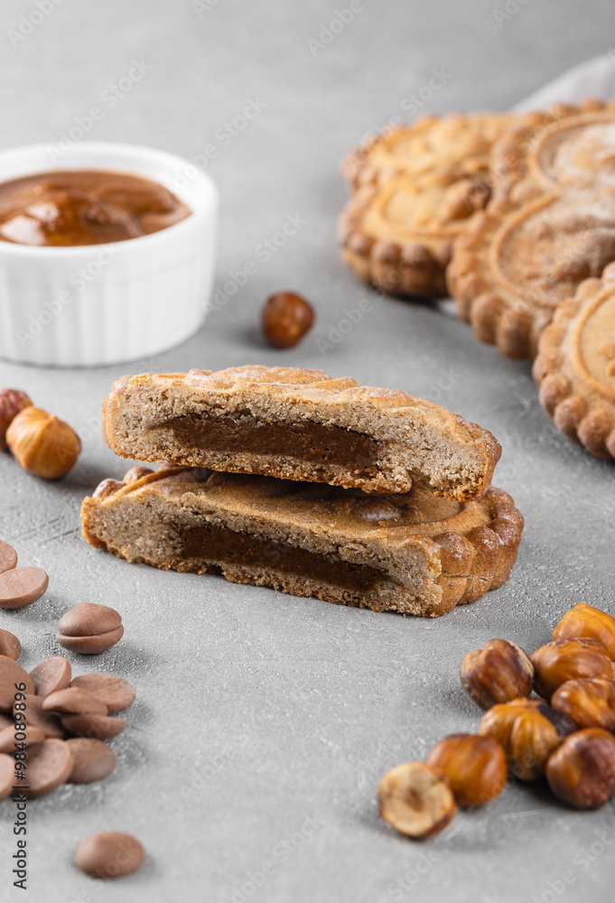 Sliced gingerbread cookies with chocolate and nut filling on a gray background. Home baking concept. Sliced gingerbread cookies with chocolate and nut filling on a gray background. Home baking concept.