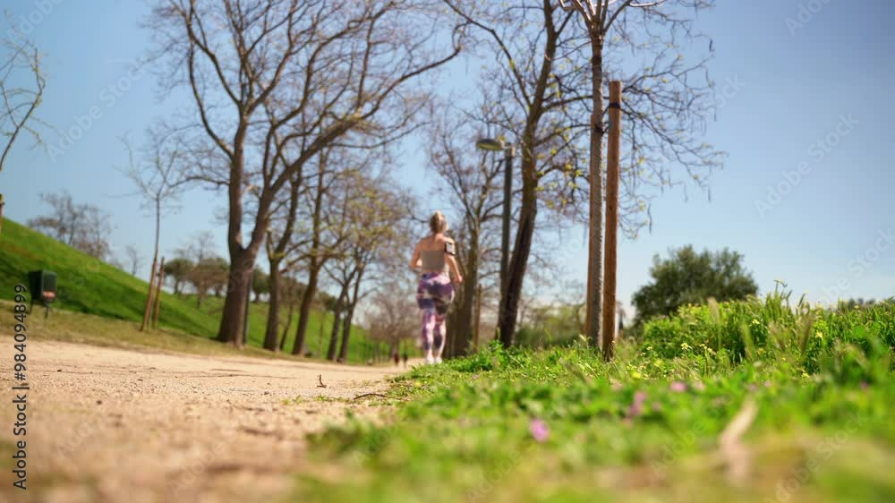 Young woman jogging along a tree-lined path in the park Young woman jogging along a tree-lined path in the park