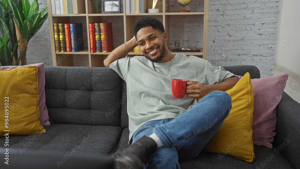 Smiling man holding mug on sofa in cozy living room Smiling man holding mug on sofa in cozy living room