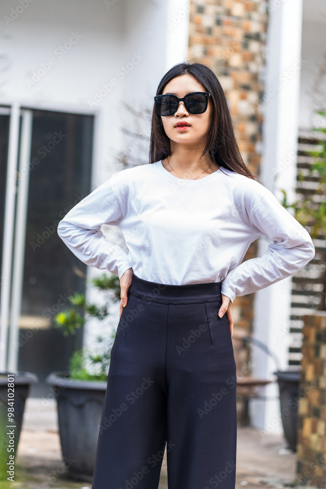 White Long Sleeve Shirt Mockup: Woman with Glasses Striking a Pose Outdoors White Long Sleeve Shirt Mockup: Woman with Glasses Striking a Pose Outdoors