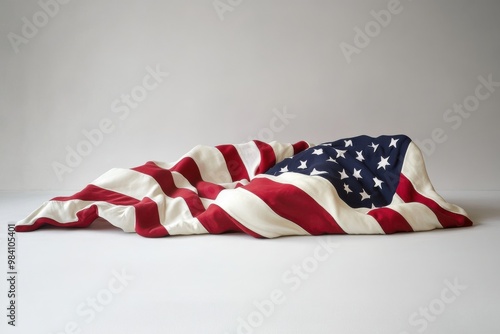 A neatly folded American flag resting on a plain white background, the edges of the fabric