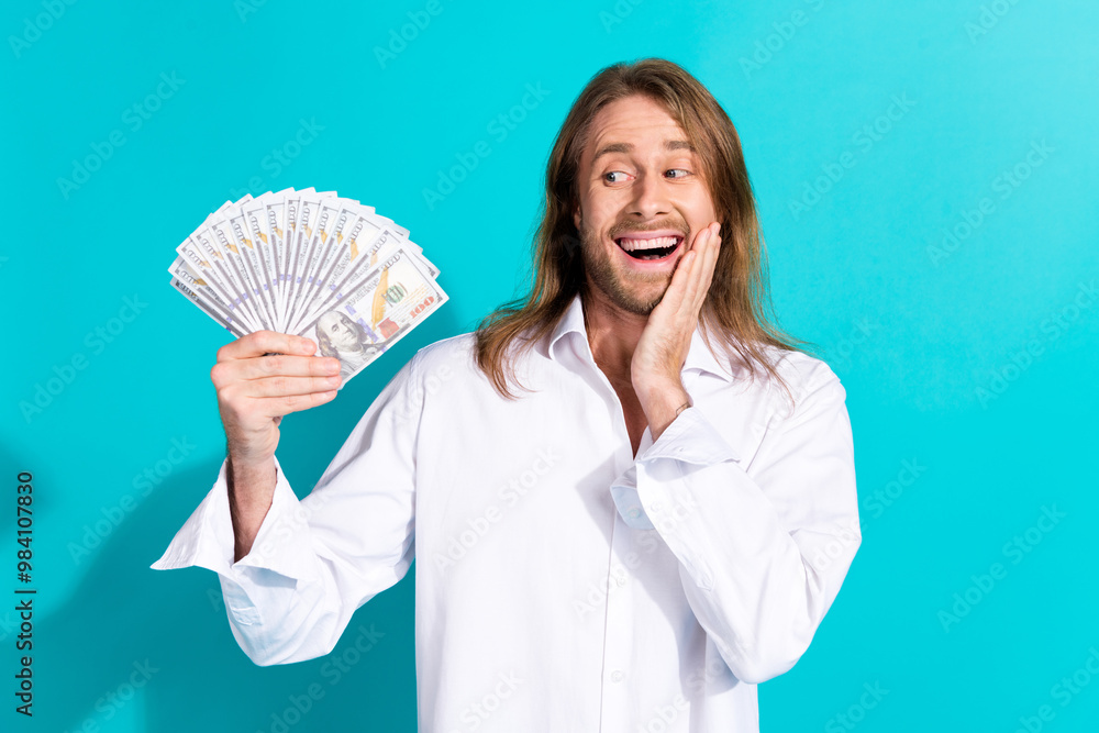 Photo of excited good mood guy wear white shirt holding money fan emtpy space isolated blue color background Photo of excited good mood guy wear white shirt holding money fan emtpy space isolated blue color background