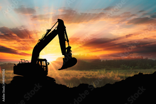 Excavators are digging the soil in the construction site on the sunset background,With image silhouette backhoe