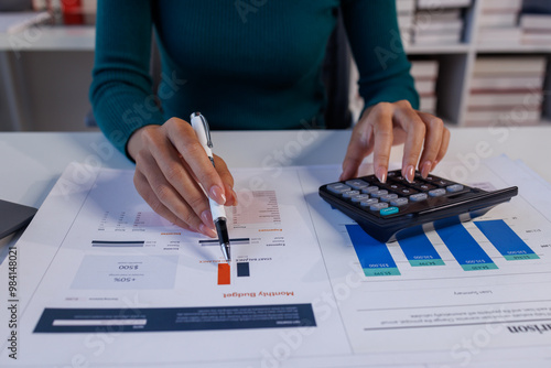 Close up of female hand accountan using a laptop computer and calculator to calculate taxes at desk in the office financial business, calculating accounting online marketing. photo