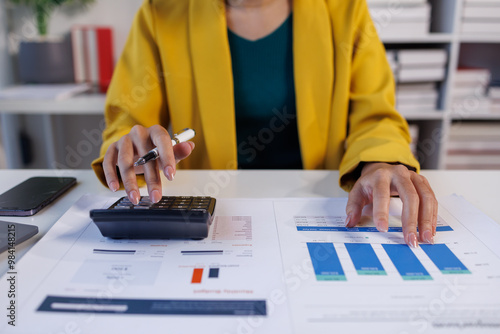 Close up of female hand accountan using a laptop computer and calculator to calculate taxes at desk in the office financial business, calculating accounting online marketing. photo