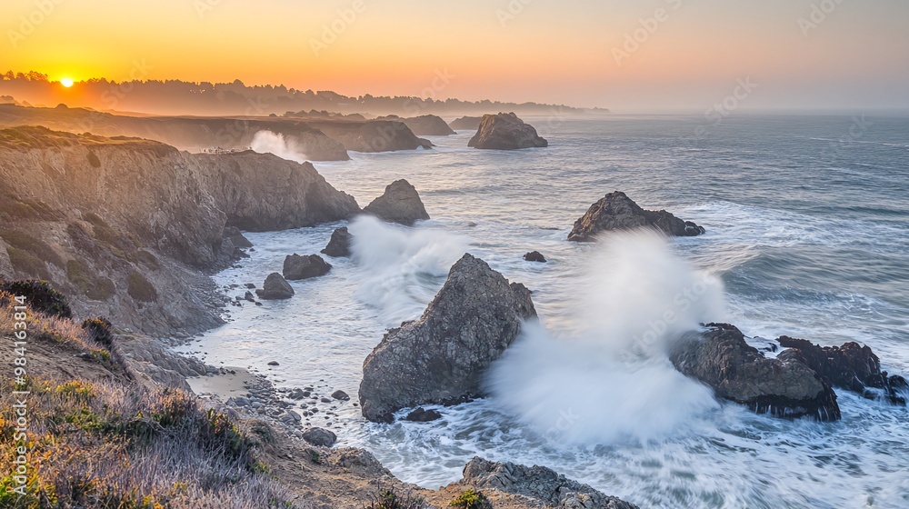 Fototapeta premium A scenic sunset over the ocean with waves crashing against rocky cliffs.