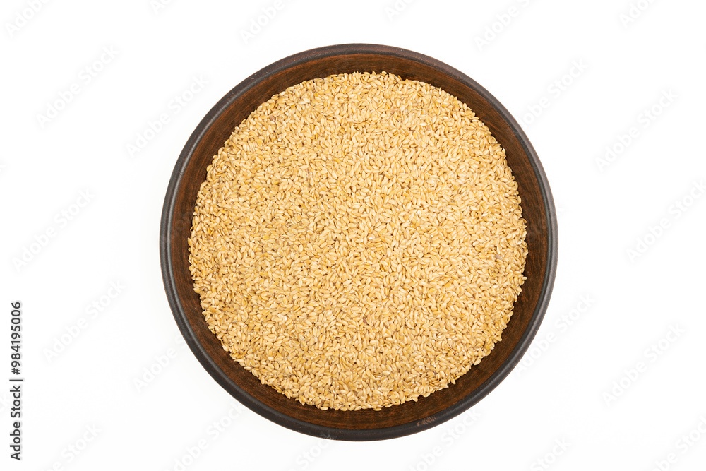 A plate of golden flax seeds on a white background A plate of golden flax seeds on a white background