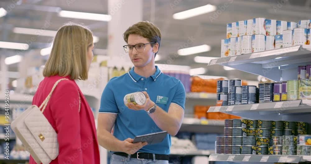 Woman in Red Blazer Receiving Assistance From a Supermarket Manager in a Blue Polo Shirt, Discussing Product Details, Nutritional Value and Discounts. Worker Showing Information on a Tablet Computer Woman in Red Blazer Receiving Assistance From a Supermarket Manager in a Blue Polo Shirt, Discussing Product Details, Nutritional Value and Discounts. Worker Showing Information on a Tablet Computer