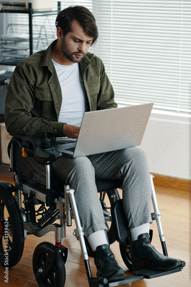 Manager with disability sitting in wheelchair and working online on laptop Manager with disability sitting in wheelchair and working online on laptop