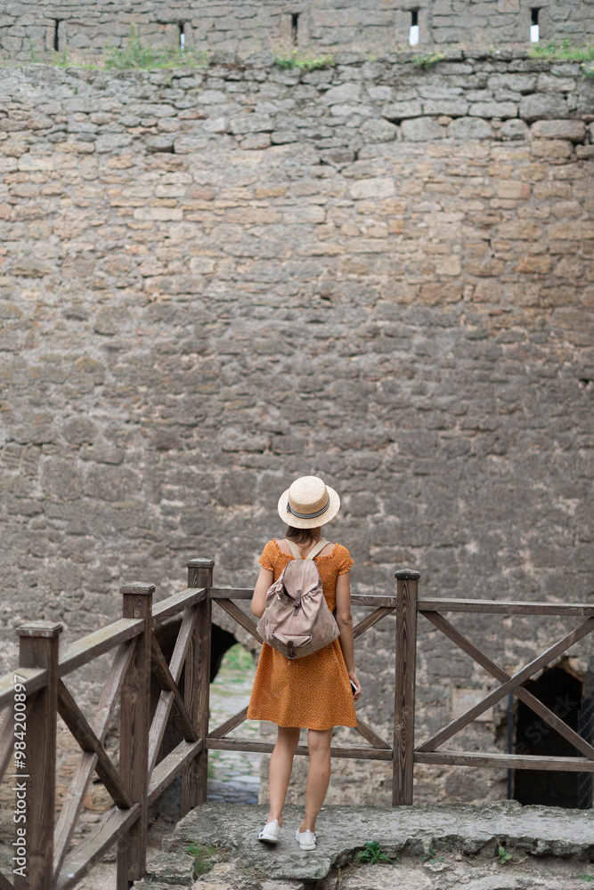 Fototapeta premium Tourist woman standing in ancient citadel fortress on stone wall background