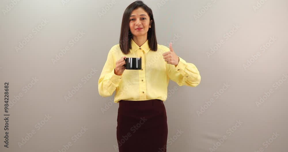 Beautiful young woman drinking tea, smiling and showing thumbs up isolated on grey background. Beautiful young woman drinking tea, smiling and showing thumbs up isolated on grey background.