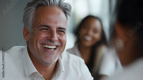 Portrait of a smiling man with gray hair wearing a white shirt