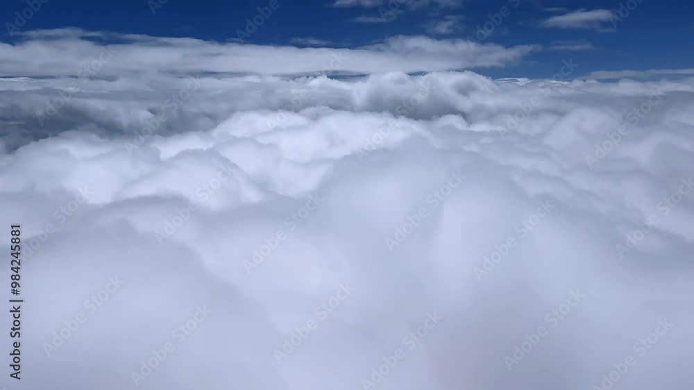 Fluffy white clouds below a bright blue sky in daytime, peaceful atmosphere, aerial view Fluffy white clouds below a bright blue sky in daytime, peaceful atmosphere, aerial view