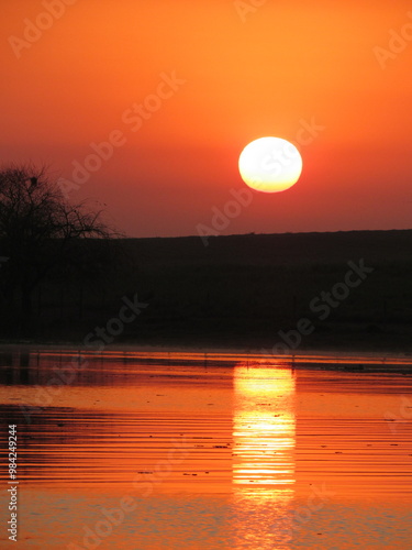 Different sunrise. Sun rising behind the hill and reflecting in the waters of the river. photo