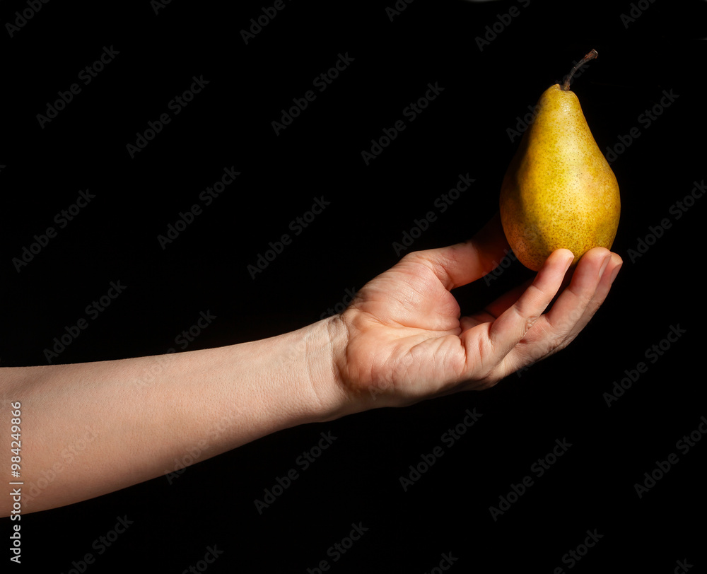 yellow pear in hand on black background yellow pear in hand on black background