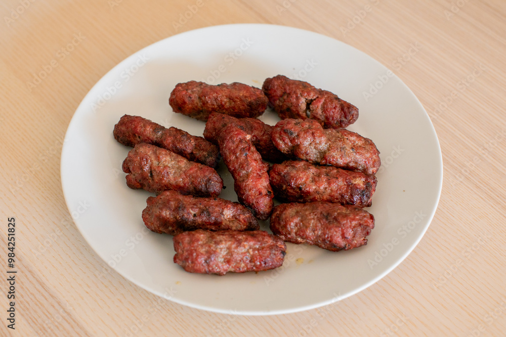 Grilled Romanian mici sausages on a white plate, perfect for barbecue gatherings and traditional holiday celebrations like Easter Grilled Romanian mici sausages on a white plate, perfect for barbecue gatherings and traditional holiday celebrations like Easter