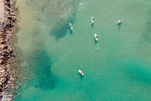Wallpaper Mural Aerial view by drone of people practicing Stand Up Paddle or SUP in Mediterranean turquoise clear sea. Torontodigital.ca