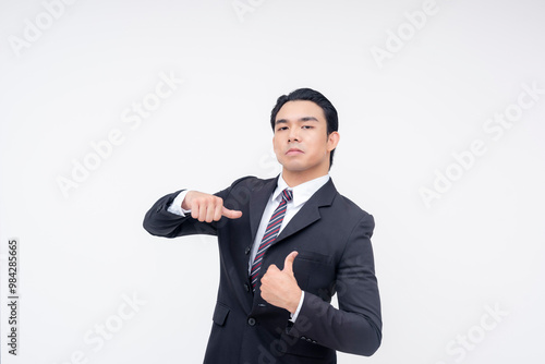 A cocky and insecure young asian business executive pointing to himself,making thumbs up sign. Isolated on a white background.