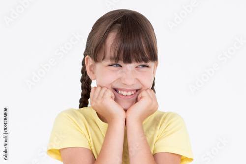 Headshot of pleased high spirit pretty female model, has warm pleasant smile, keeps hands under chin, wears yellow t-shirt, isolated over white background. Happiness concept