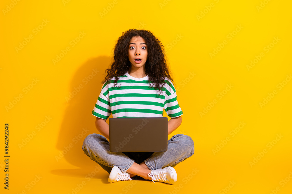 Full body portrait of nice young girl laptop stare wear striped t-shirt isolated on yellow color background Full body portrait of nice young girl laptop stare wear striped t-shirt isolated on yellow color background
