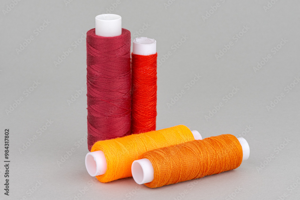 Red orange pink thread spools on grey background. Red orange pink thread spools on grey background.