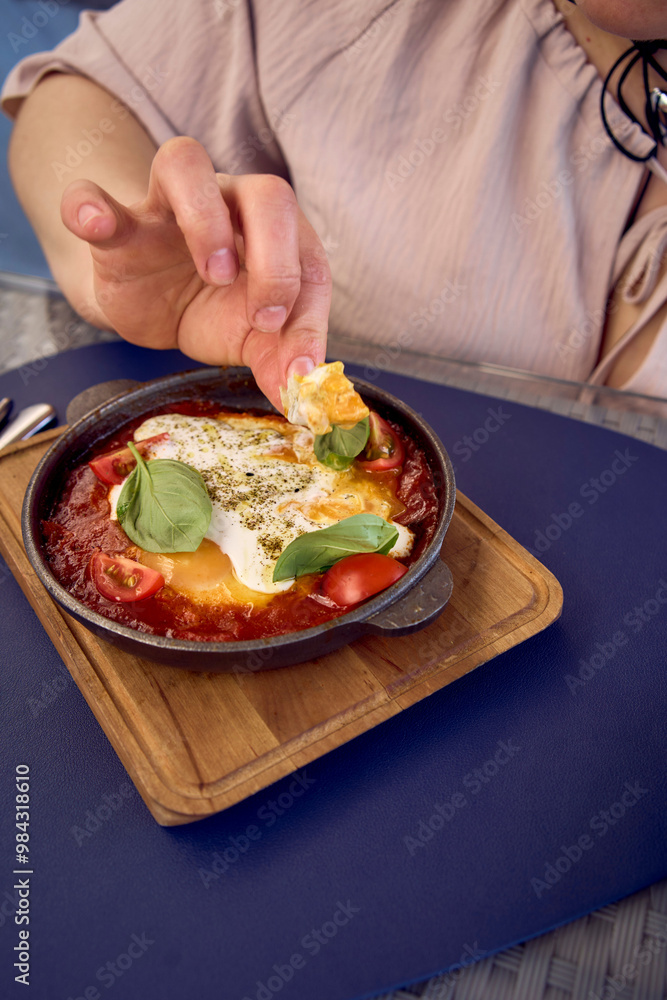 medium sized woman in peach fuzz dress eating Shakshouka in modern restaurant medium sized woman in peach fuzz dress eating Shakshouka in modern restaurant