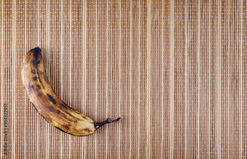 An overripe banana lies on a bamboo napkin. photo