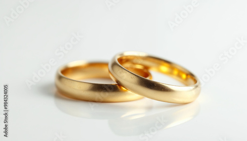 A macro shot captures elegant gold wedding rings on a pristine white background, highlighting their shine.