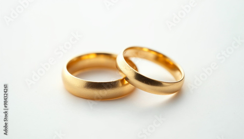 A macro shot captures elegant gold wedding rings on a pristine white background, highlighting their shine.