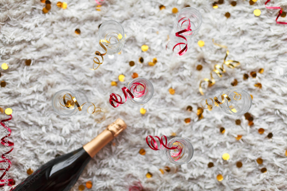 Obraz premium a bottle of champagne and glasses for champagne for christmas, new year, party, wedding celebration with gold red confetti and decoration