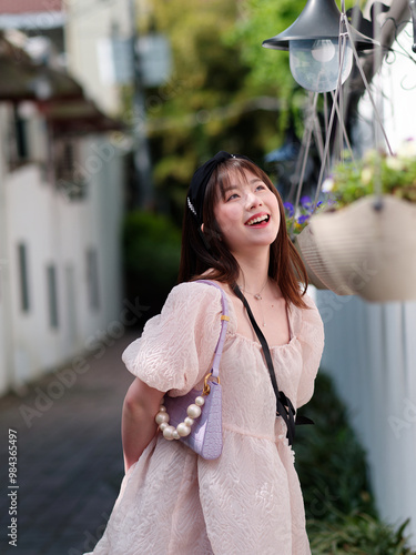 Beautiful young Chinese woman smiling in sunny summer day, wearing cute pink dress. Emotions, people, beauty, youth and lifestyle portrait, street photography.