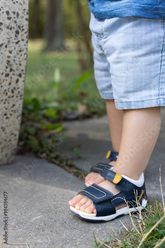 Little child walks in too small sandals.  photo