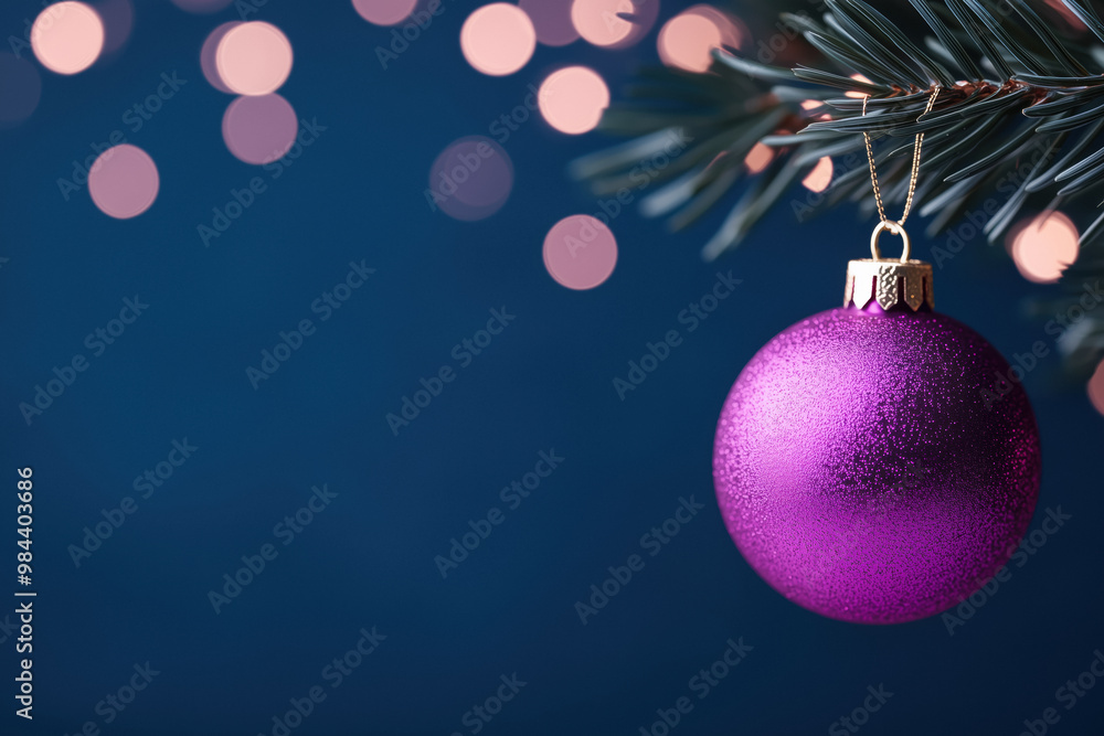 Purple Christmas ornament hanging from a pine branch with warm bokeh lights in the background, set against a deep blue festive backdrop. Purple Christmas ornament hanging from a pine branch with warm bokeh lights in the background, set against a deep blue festive backdrop.