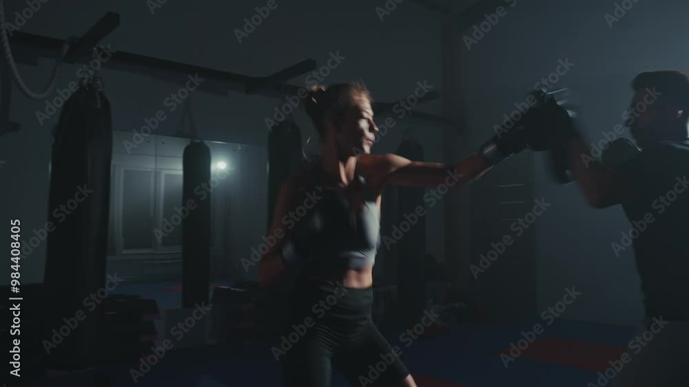 Boxing training session in a dimly lit gym with a focus on technique and teamwork Boxing training session in a dimly lit gym with a focus on technique and teamwork