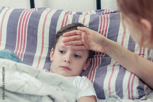 A mother measures the temperature of a sick child, carefully supporting him at the time